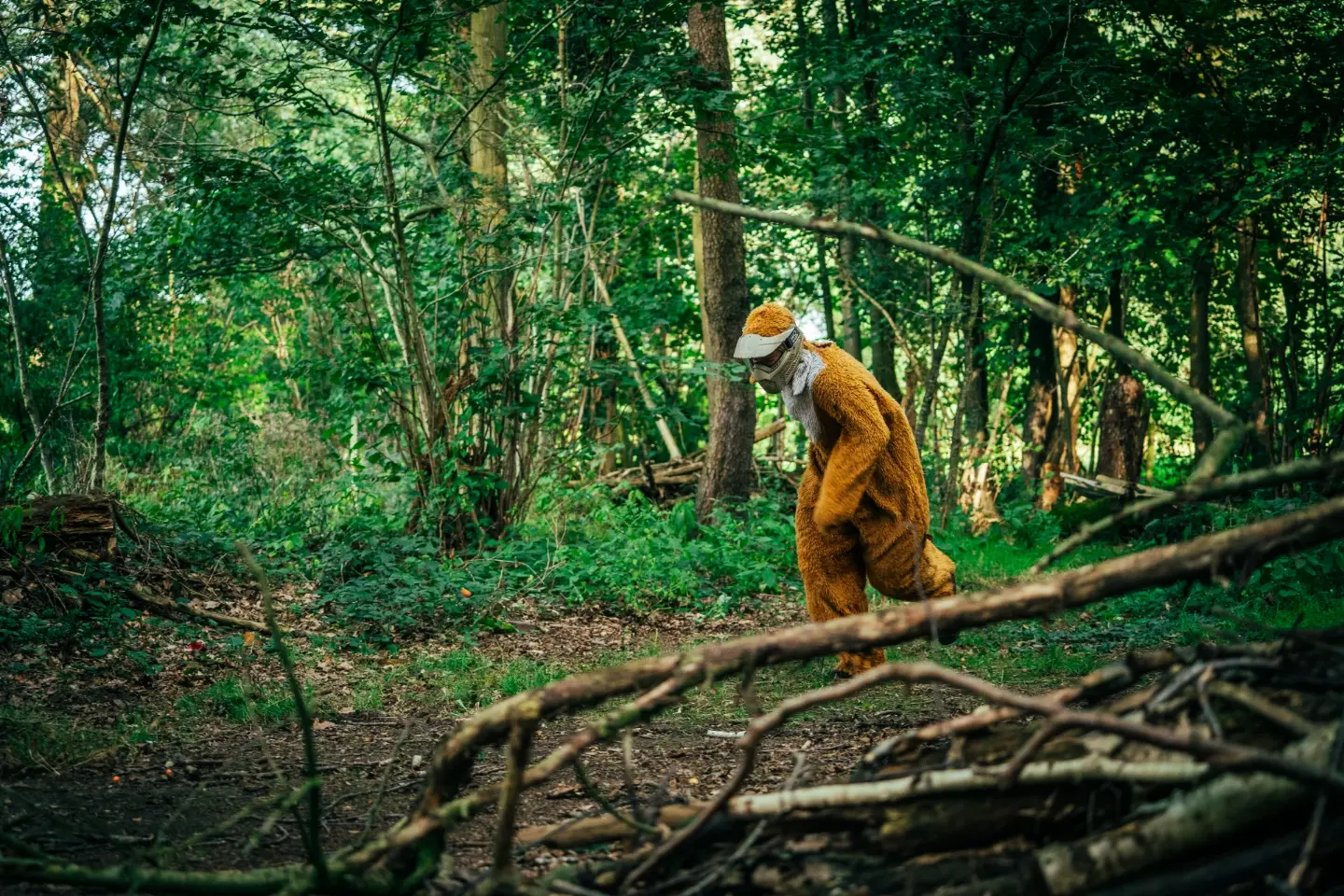 Speler in opvallend verkleedpak sluipt door het bos tijdens een paintballspel