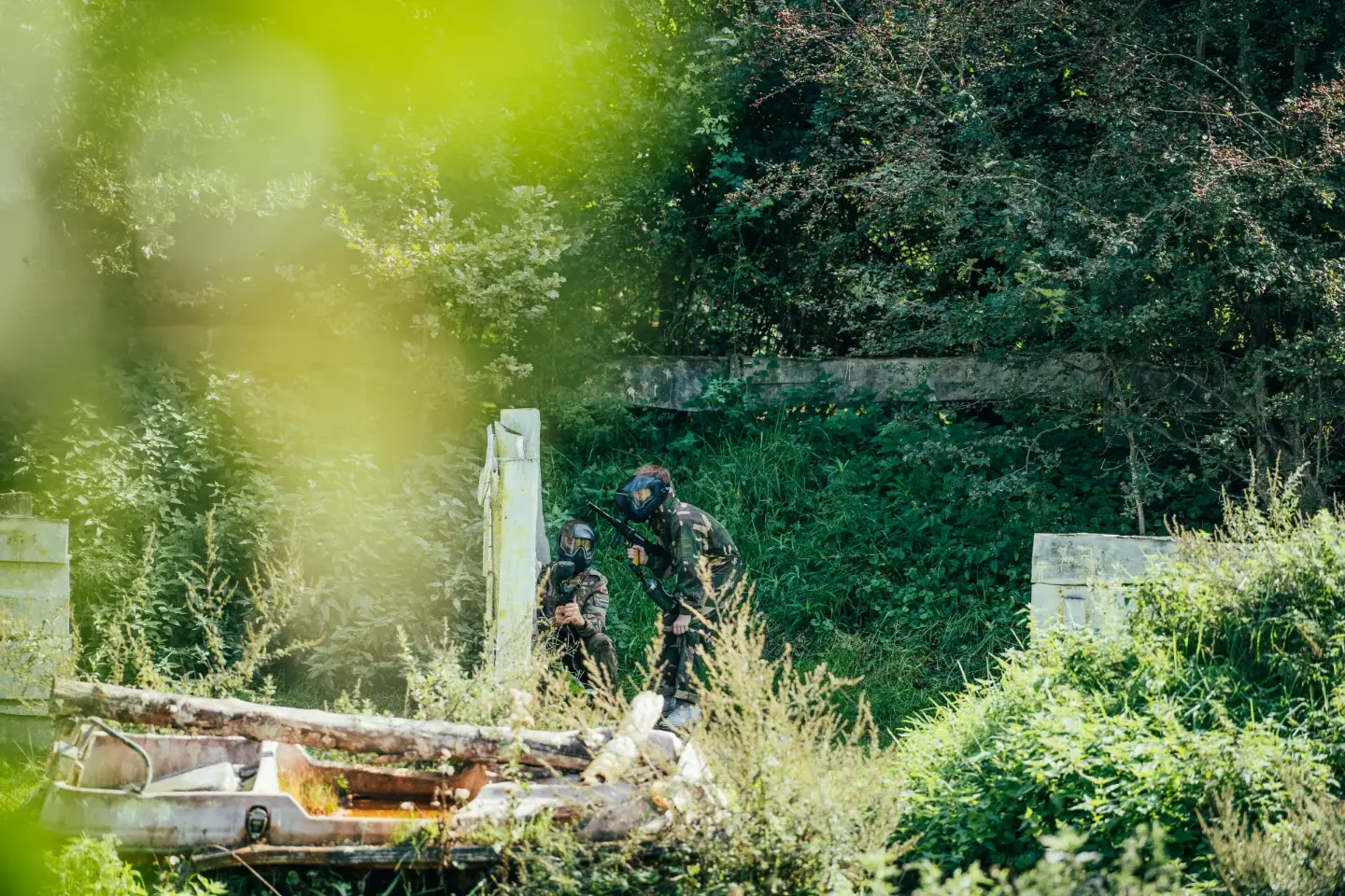 Twee paintballspelers zoeken dekking op het bosrijke speelveld