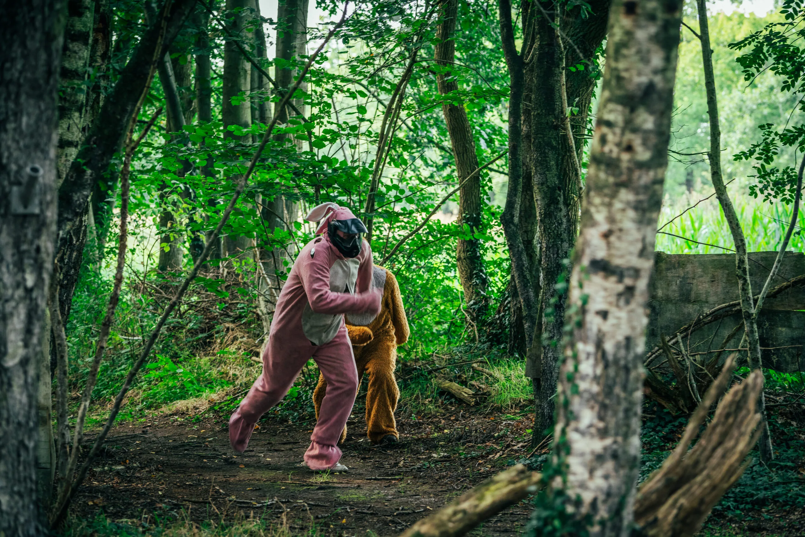 Vrijgezel in roze konijnenpak sluipt met een medespeler door het bos tijdens een paintballuitje vanuit Markelo