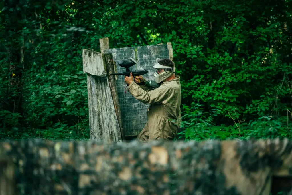 Paintballspeler mikt vanachter een houten bunker op het speelveld vlakbij Oldenzaal